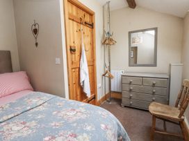 A bedroom with a bed, dresser, mirror, and chair at Copper Miners Cottage, Beddgelert, Eryri (snowdonia)