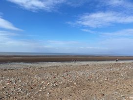 A beach with pebbles and people walking at Sun House in Allonby