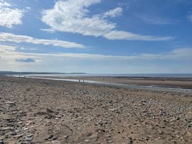 A beach with people walking along the shoreline at Sun House in Allonby