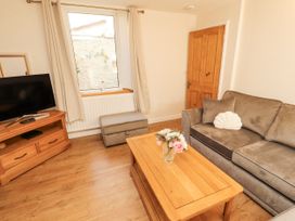 A living room with a sofa and a television at Sun House in Allonby