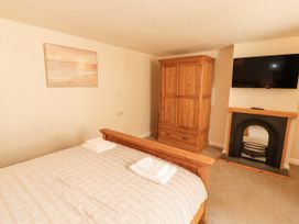 A bedroom with a bed and wooden wardrobe at Sun House Allonby