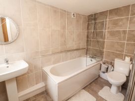 A bathroom featuring a bathtub, toilet, sink, and mirror at Sun House in Allonby