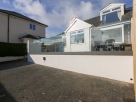 An outdoor area with a glass railing and seating at Swn Y Don in Llanbedrog