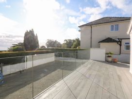 An outdoor area with decking and a glass railing at Swn Y Don in Llanbedrog