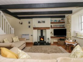 A living room with a TV and fireplace at Driftwood Cottage in St. Austell