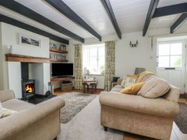 A living room with a fireplace and television at Driftwood Cottage in St. Austell