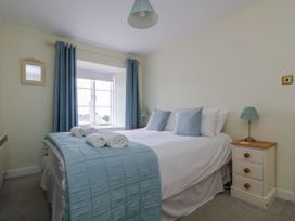 A bedroom with a bed and bedside table at Driftwood Cottage in St. Austell