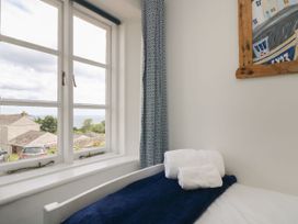 A bedroom with a window and towels on a bed at Driftwood Cottage in St. Austell