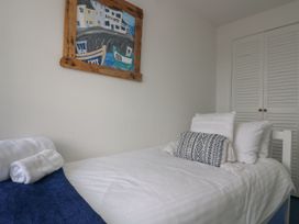 A bedroom with a bed, towels, and artwork at Driftwood Cottage in St. Austell