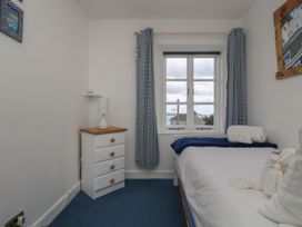 A bedroom with a bed and window at Driftwood Cottage in St. Austell