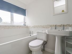 A bathroom with a bathtub, toilet, and sink at Driftwood Cottage in St. Austell
