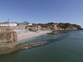 A beach with a pier and cliff at Driftwood Cottage in Porthpean