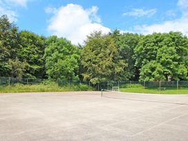 A tennis court with a net and trees at Valley Lodge 2 in Callington