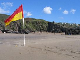 A beach with a flag and people enjoying in the background at Valley Lodge 2 in Callington