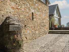An outdoor area with a stone wall and a sign at Lower Velwell Barn in Totnes