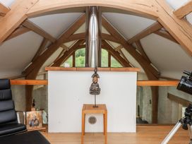A loft with wooden beams and a decorative statue at Lower Velwell Barn in Totnes