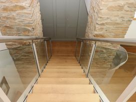 A staircase with wooden steps and glass railing at Lower Velwell Barn in Totnes
