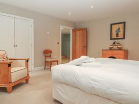 A bedroom with a bed and armchair at Lower Velwell Barn in Totnes