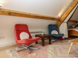 A living room with red and blue chairs and a coffee table at Lower Velwell Barn in Totnes