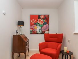 A snug with an armchair and a painting at Lower Velwell Barn in Totnes