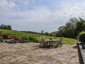A garden with a dining table and chairs at Lower Velwell Barn in Totnes