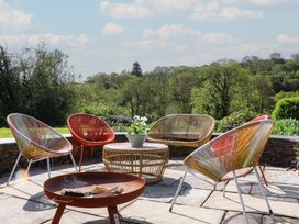 An outdoor seating area with chairs and a table at Lower Velwell Barn in Totnes