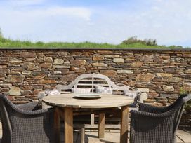 An outdoor dining area with a stone wall at Lower Velwell Barn in Totnes