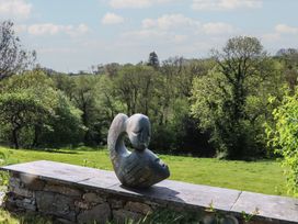 A sculpture on a stone bench overlooking a grassy area at Lower Velwell Barn, Totnes