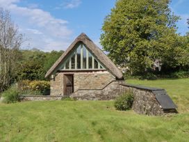 A house with a thatched roof and stone walls at Lower Velwell Barn in Totnes