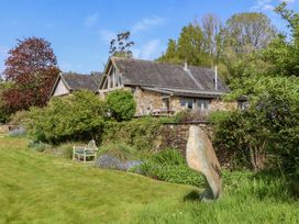 A house and garden with a stone sculpture at Lower Velwell Barn in Totnes