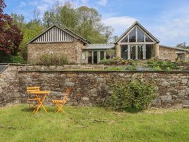 An outdoor area with a stone wall and an orange table at Lower Velwell Barn, Totnes