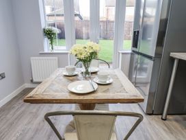 A kitchen with a wooden table set for two at Pearl Stone House in Whitby