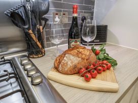 A kitchen counter with bread, tomatoes, wine, and glasses at Pearl Stone House, Whitby