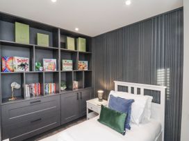 A bedroom with a bed and shelving containing books and games at Pearl Stone House in Whitby