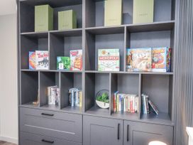 A living room with shelves containing games and books at Pearl Stone House in Whitby
