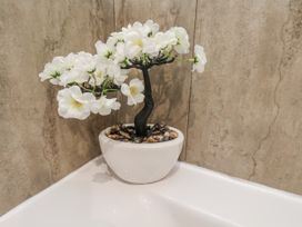 An artificial plant in a flower pot next to a bathtub at Pearl Stone House in Whitby