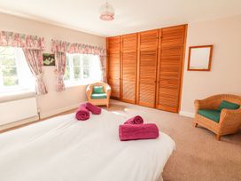 A bedroom with a bed, towels, and wardrobe at Tremorla in Boscastle