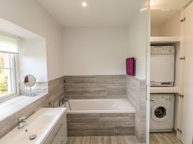 A bathroom with a bath and washing machine at Tremorla in Boscastle