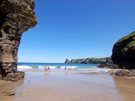 A beach with rock formations and people in the water at Tremorla in Boscastle