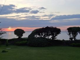 A garden with trees and a view of the sunset at Tremorla in Boscastle