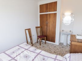 A bedroom with a bed, chair, mirror, wardrobe, and sink at No.1 Vanderhoof Way in Saundersfoot