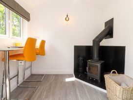 A dining area with bar stools and a wood stove at Shepherds Hut 1