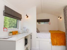 A bedroom with a bed and kitchen appliances at Shepherds Hut 1