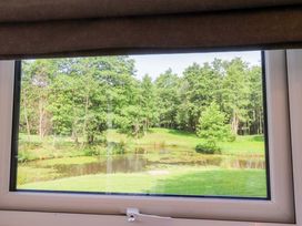A view of trees and a pond from a window at Shepherds Hut 1