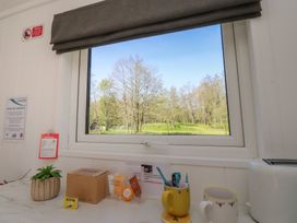 A kitchen with a window showing greenery and various items on the counter at Butterfly Hut 1 Forton near Garstang