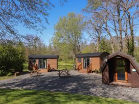Three wooden cabins with benches in an outdoor area at Butterfly Hut 1 Forton near Garstang