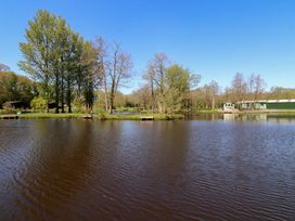 A view of water with trees and cabins at Butterfly Hut 1 Forton near Garstang