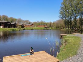 A view of a pond with wooden cabins at Butterfly Hut 1 Forton near Garstang