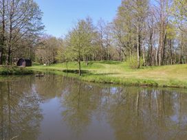 A pond with trees and a cabin at Butterfly Hut 1 Forton near Garstang