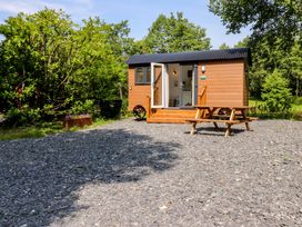 A wooden shepherd's hut with a table and bench outside at Shepherds Hut 2